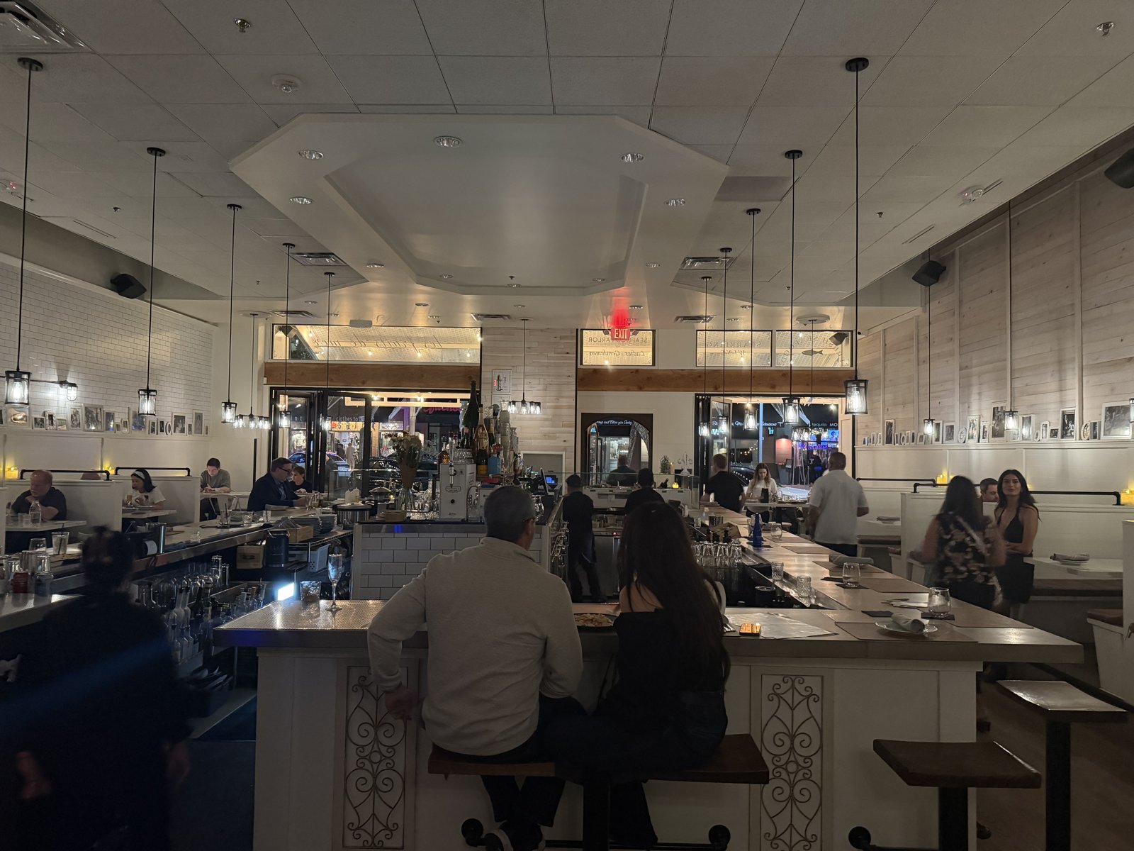 Inside Humble Oysters & Bubbles: the central bar under pendant lights and white subway tile