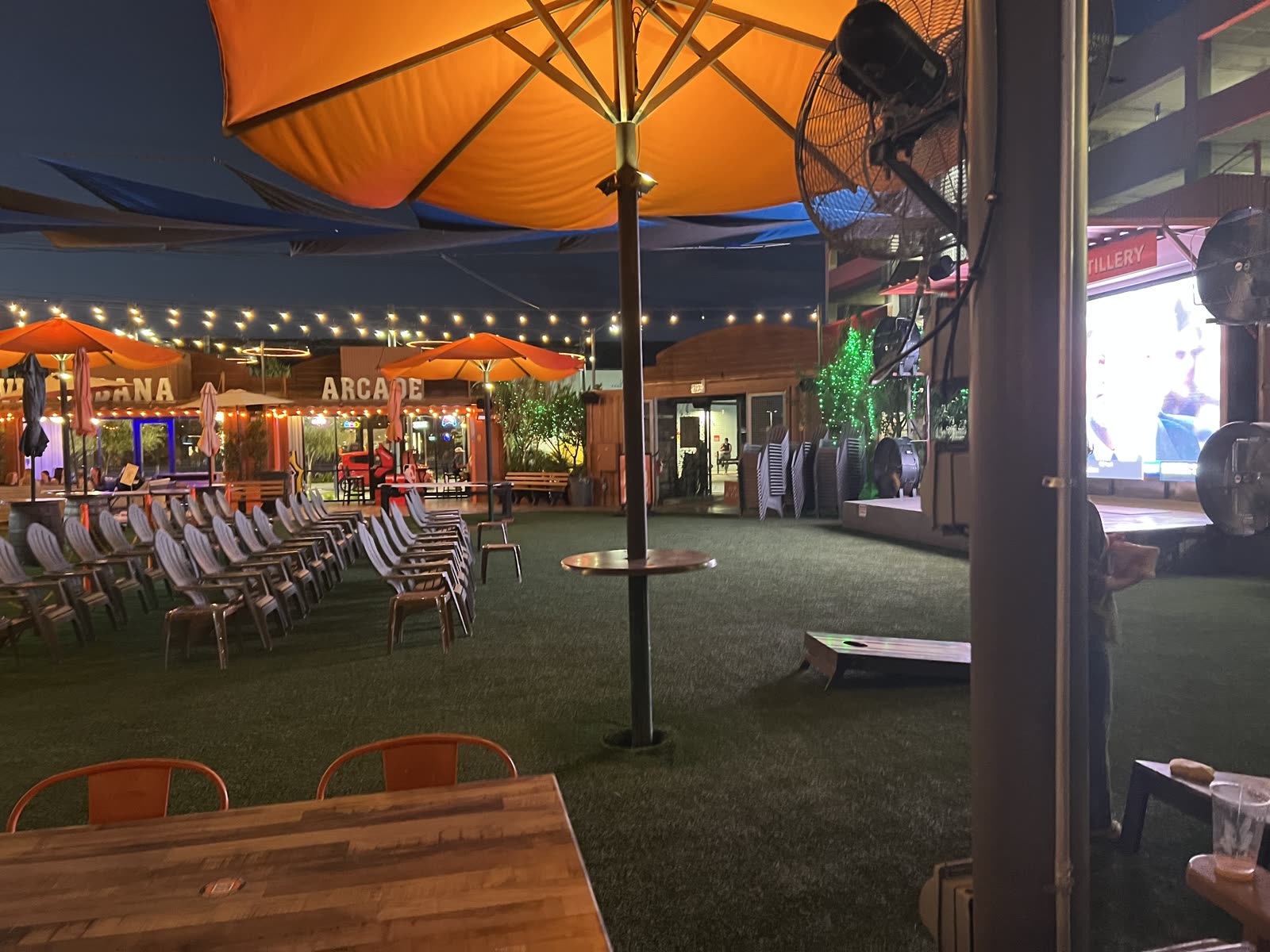 Evening lawn at OHSO Gilbert with lounge chairs facing the big screen, cornhole and the arcade